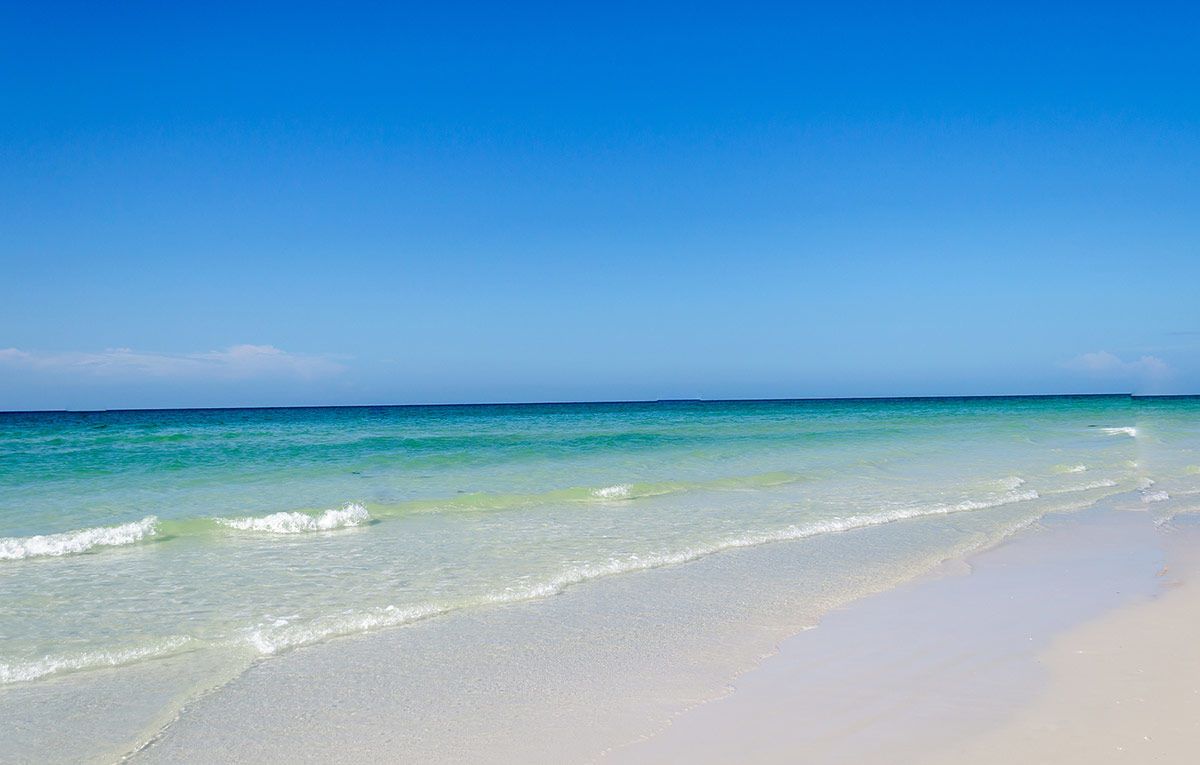 A beach with clear turquoise water and white sand.