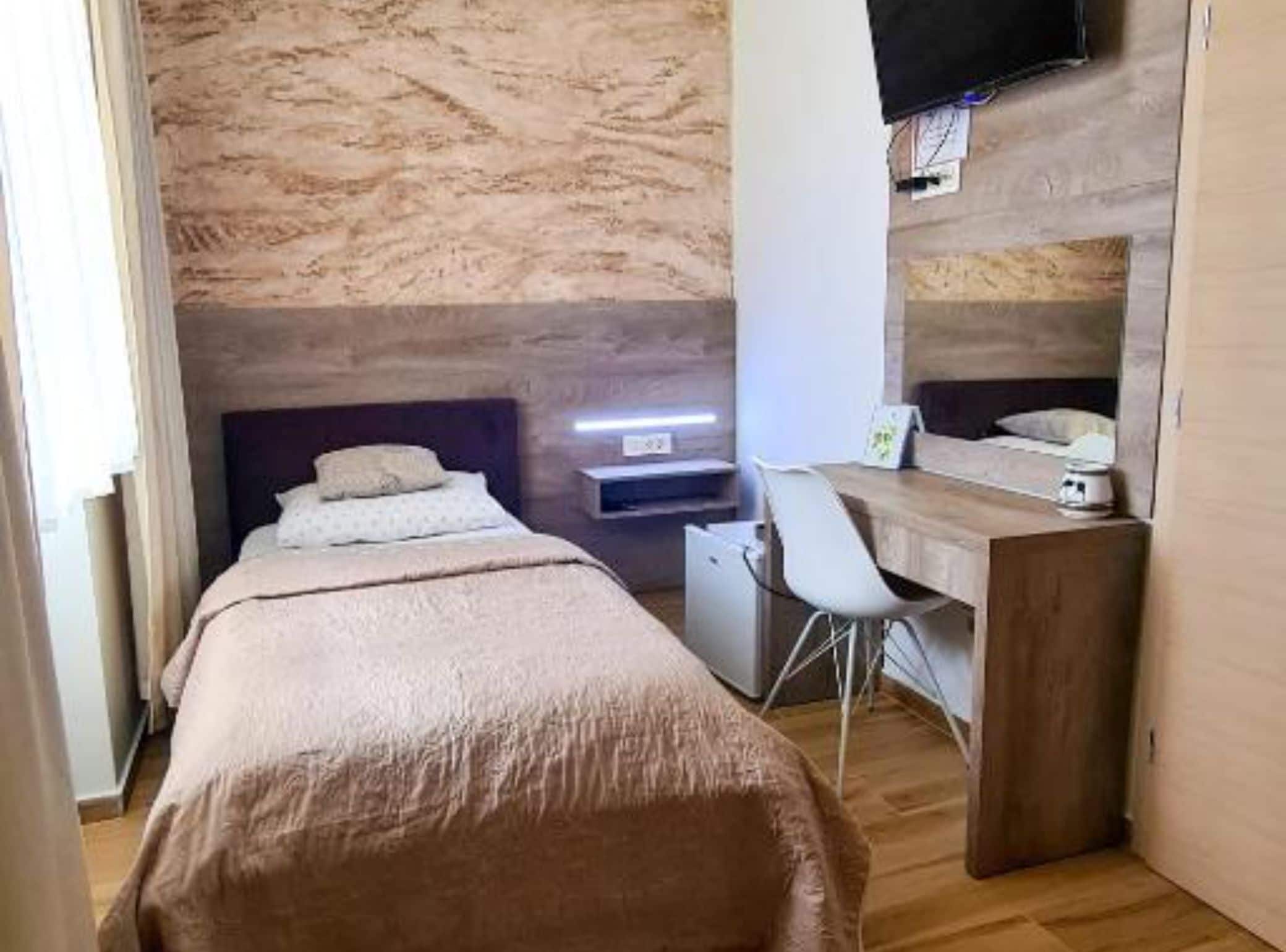A bedroom with a bed, a desk, and a chair.