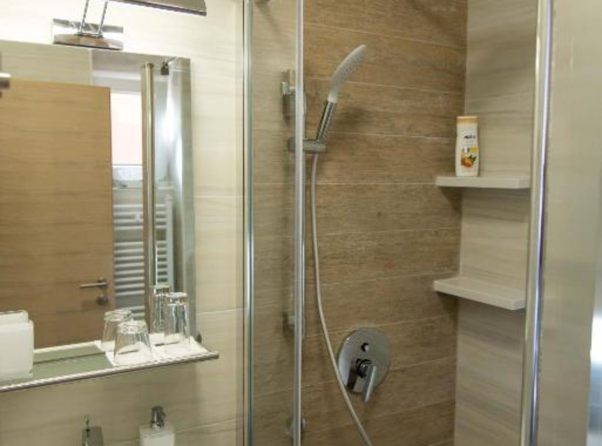 Ein modernes Badezimmer mit Duschkabine aus Glas, einem Spiegel und einem Ablagefach mit Toilettenartikeln.