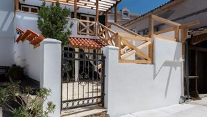 Edifício residencial em construção com vigas de madeira aparentes, telhado em telhas e portão de acesso.