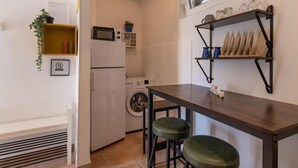 Uma cozinha compacta com máquina de lavar, micro-ondas e um armário com louças.