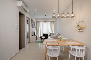 A modern living room with a dining area, a sofa, a coffee table, and a chandelier. - Iconic Regency Service Residences, Managed by Iconic Hotel (Gelugor)