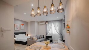 Ein modernes Hotelzimmer mit Bett, Sofa, Esstisch und Pendelleuchten.