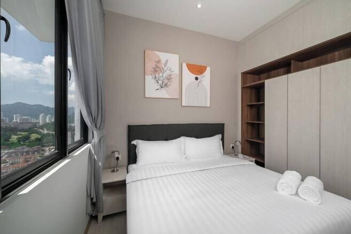 Een moderne hotelkamer met een groot bed, een nachtkastje, een garderobe en twee kunstwerken aan de muur.