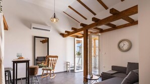 A living room with a sofa, a rocking chair, a small table, and a hanging light fixture. - Apartment Sea&sunset View (Novalja)