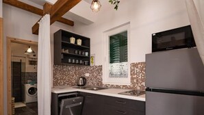 A compact kitchen with dark cabinets, a stainless steel refrigerator, and a tiled backsplash. - Apartment Sea&sunset View (Novalja)