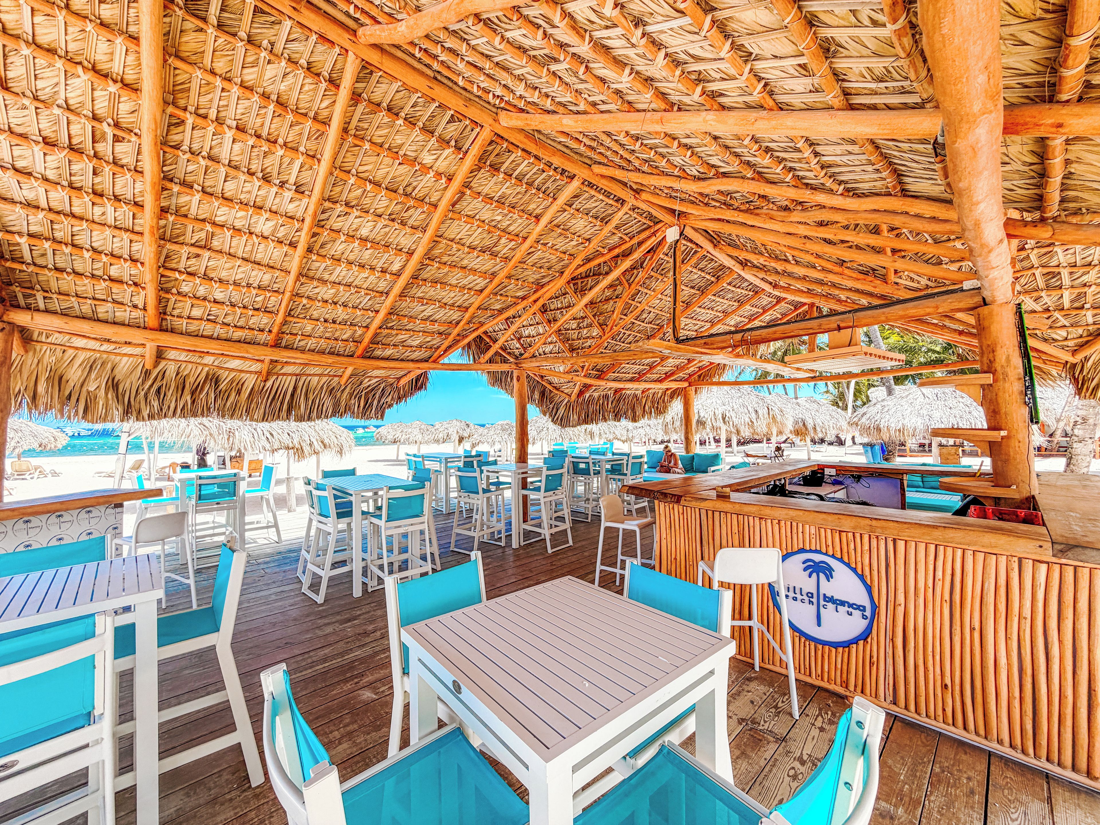 Un restaurant situé en bord de mer, doté d’une terrasse, d’un toit de chaume et d’un espace piscine.