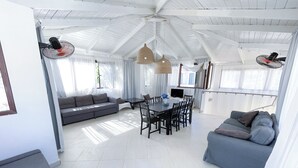 A spacious living area with a dining table, sofas, and ceiling fans. - BEACH FUN AND LIFE (Punta Cana)