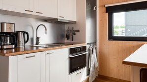 A modern kitchen with white cabinets, stainless steel appliances, and a wooden countertop.