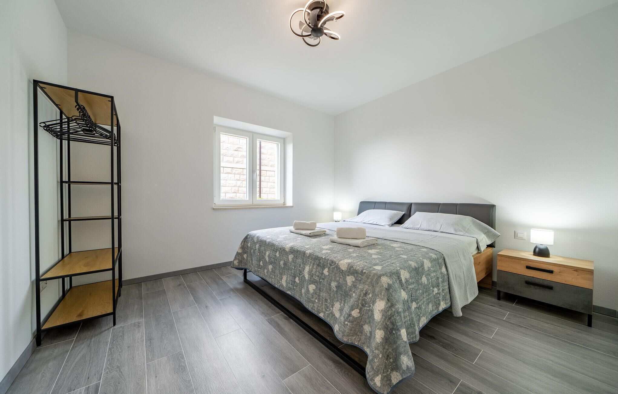 Een slaapkamer met een bed, nachtkastjes, een raam, een plafondventilator en een inbouwkast.