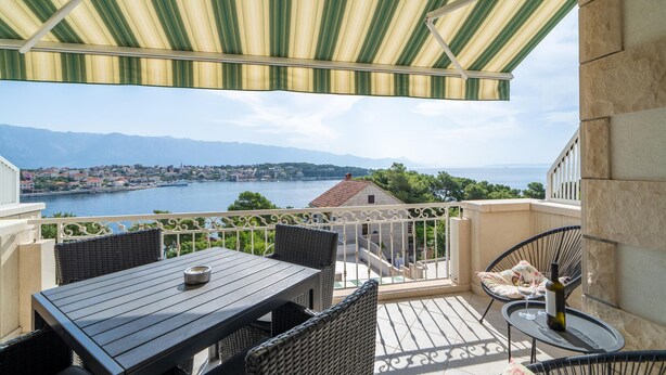 A balcony with a view of a lake and mountains, furnished with wicker chairs and a table. - Gorgeous apartment in Selca with WiFi (Selca)