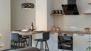 A modern kitchen with a Bosch oven, a built-in microwave, and a black range hood. There are two bar stools and a wine bottle on the counter. - Gorgeous apartment in Selca with WiFi (Selca)
