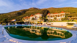 Zona de piscina con el reflejo de un edificio y una montaña al fondo.