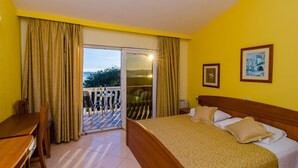Una habitación de hotel con cama, escritorio y balcón con mesa y sillas.