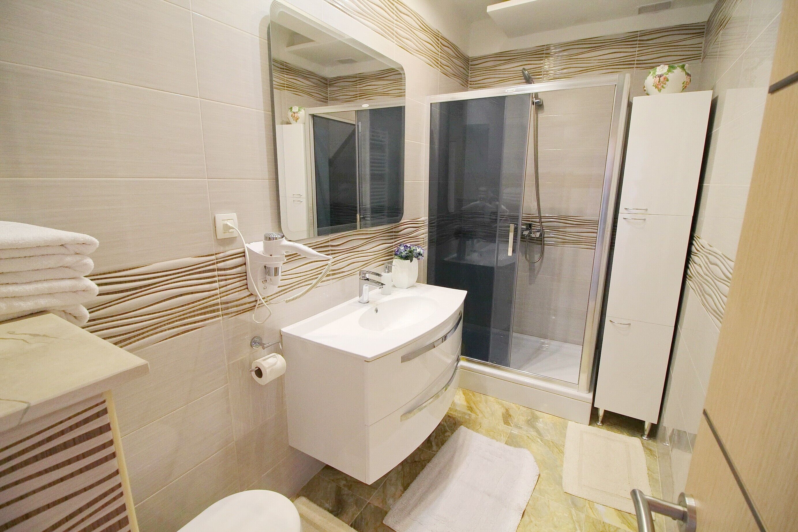 Une salle de bain moderne avec une douche à parois de verre, un lavabo blanc et des toilettes.
