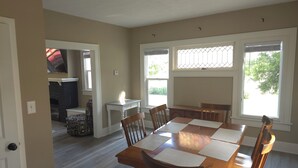 A dining area with a wooden table and chairs, a small white table, and a fireplace in the background. - Cozy 3 bedroom Farmhouse in Delaware Ohio, On the Golf Course. Near OWU! (Delaware)