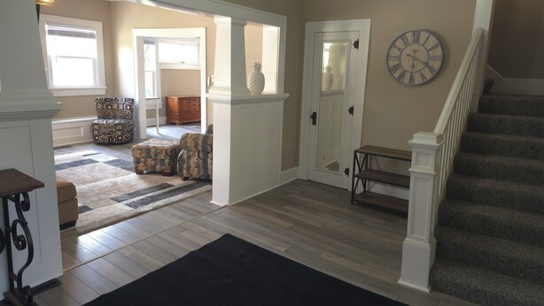 A spacious living room with a wooden floor, a black rug, and a staircase leading to another level. - Cozy 3 bedroom Farmhouse in Delaware Ohio, On the Golf Course. Near OWU! (Delaware)