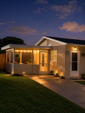 Una casa con porche cubierto, una puerta con número y exterior bien iluminado.