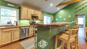 Una cocina con armarios de madera, lavavajillas de acero inoxidable y una pared verde de acento.