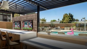 A poolside area with a covered seating area, a pool with a pink flamingo float, and a wall with sports-themed artwork. - The Jade Hill' Luxurious Penthouse Two floors Hollywood Hills Pool, Gym, Jacuzzi (Los Angeles)