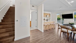 A modern kitchen with wooden cabinets, a dining area with bar stools, and a staircase leading to another level. - The Jade Hill' Luxurious Penthouse Two floors Hollywood Hills Pool, Gym, Jacuzzi (Los Angeles)