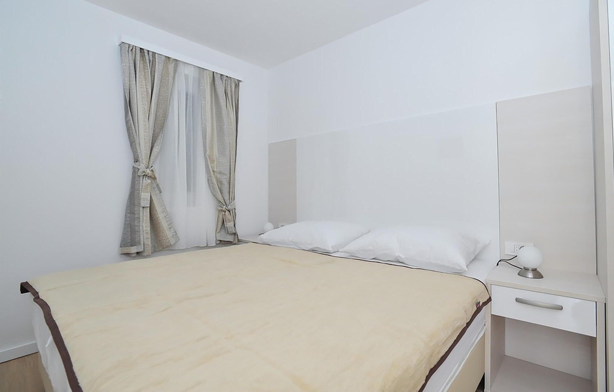 A bedroom with a bed, a bedside table, and a mirror.