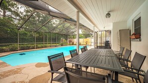 Eine Außenpatio mit Pool, überdachter Sitzgelegenheit und Blick ins grüne Umland.