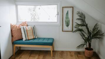 A cozy corner with a teal bench, a potted plant, and a framed leaf artwork.