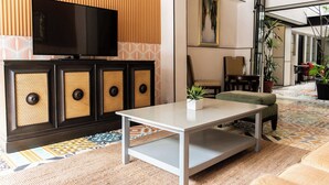 Ein modernes Wohnzimmer mit Flachbildfernseher, einer Couch, einem Couchtisch und einem gemusterten Teppich.