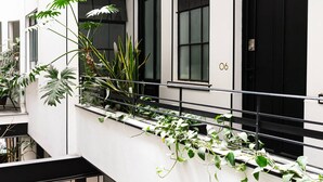 Ein modernes Gebäude mit einem Balkon, der mit verschiedenen Pflanzen geschmückt ist.