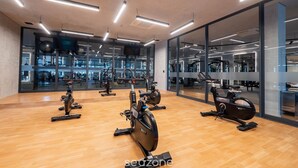 Une salle de sport équipée de vélos d’exercice, de murs recouverts de miroirs et d’un plancher en bois.