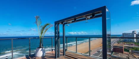 A modern balcony with a view of the ocean and a cityscape.