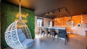Une cuisine moderne avec un fauteuil suspendu, un néon et un mur en briques.