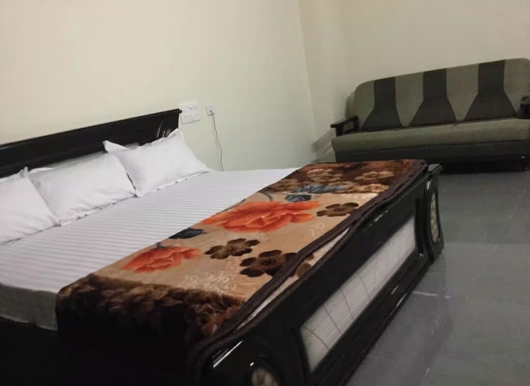 A bed with a floral bedspread, a black headboard, and white pillows.
