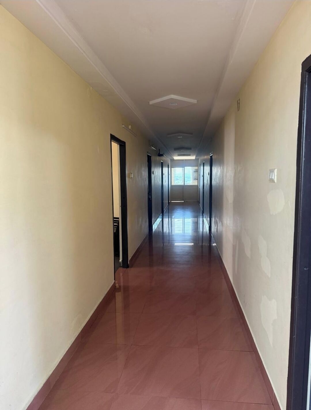 A long, narrow hallway with a tiled floor and cream-colored walls.