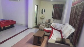 A living room with a sofa, a small table, and a red bedspread.