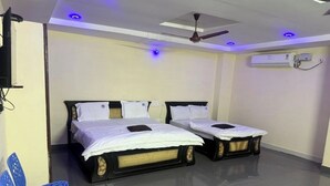 A room with two beds, a ceiling fan, and a blue chair.