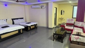 A hotel room with two beds, a sofa, a coffee table, and a ceiling fan.
