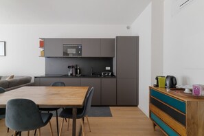 Una cocina moderna con armarios grises, un microondas y una cafetera. Hay una mesa de comedor de madera con sillas.