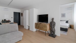 Un salon moderne avec un canapé, un téléviseur, une statue et un lit.