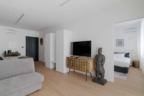 Un saló modern amb un sofà, una televisió, una estàtua i un llit.