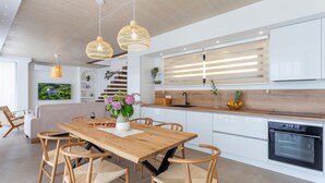 Una cucina moderna con tavolo da pranzo in legno, sedie in vimini e lampade a sospensione.