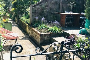 Un jardin avec des plates-bandes surélevées, une table en bois et une chaise.