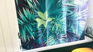Une salle de bain avec un rideau de douche orné d’un motif de feuilles tropicales.