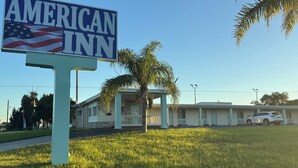 A sign for the American Inn with a clear view of the motel's exterior, including its two-story structure and adjacent parking area. - American Inn (Cocoa)