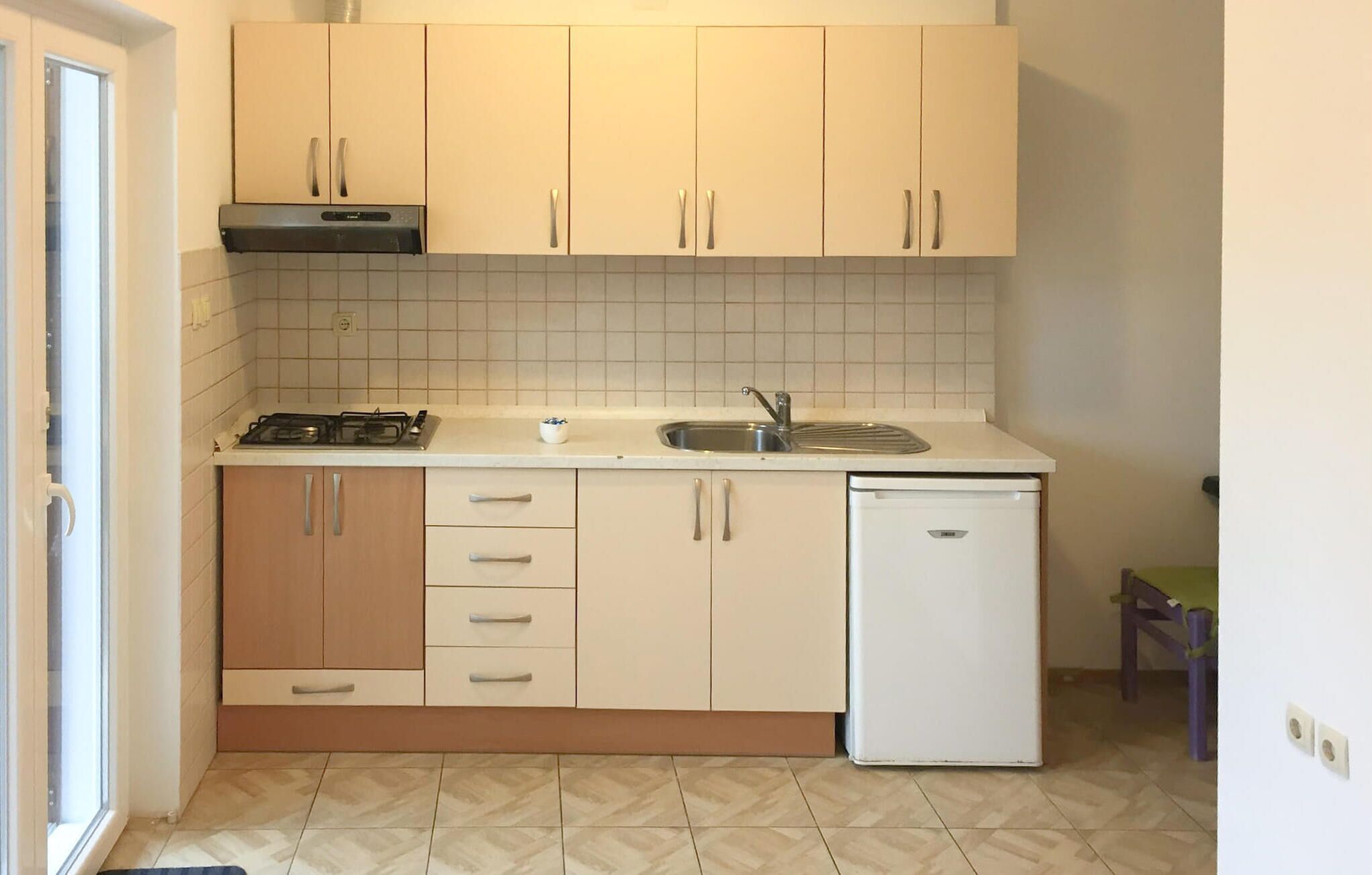 Una cucina compatta con mobili bianchi, un fornello a gas, un lavello e una lavastoviglie.