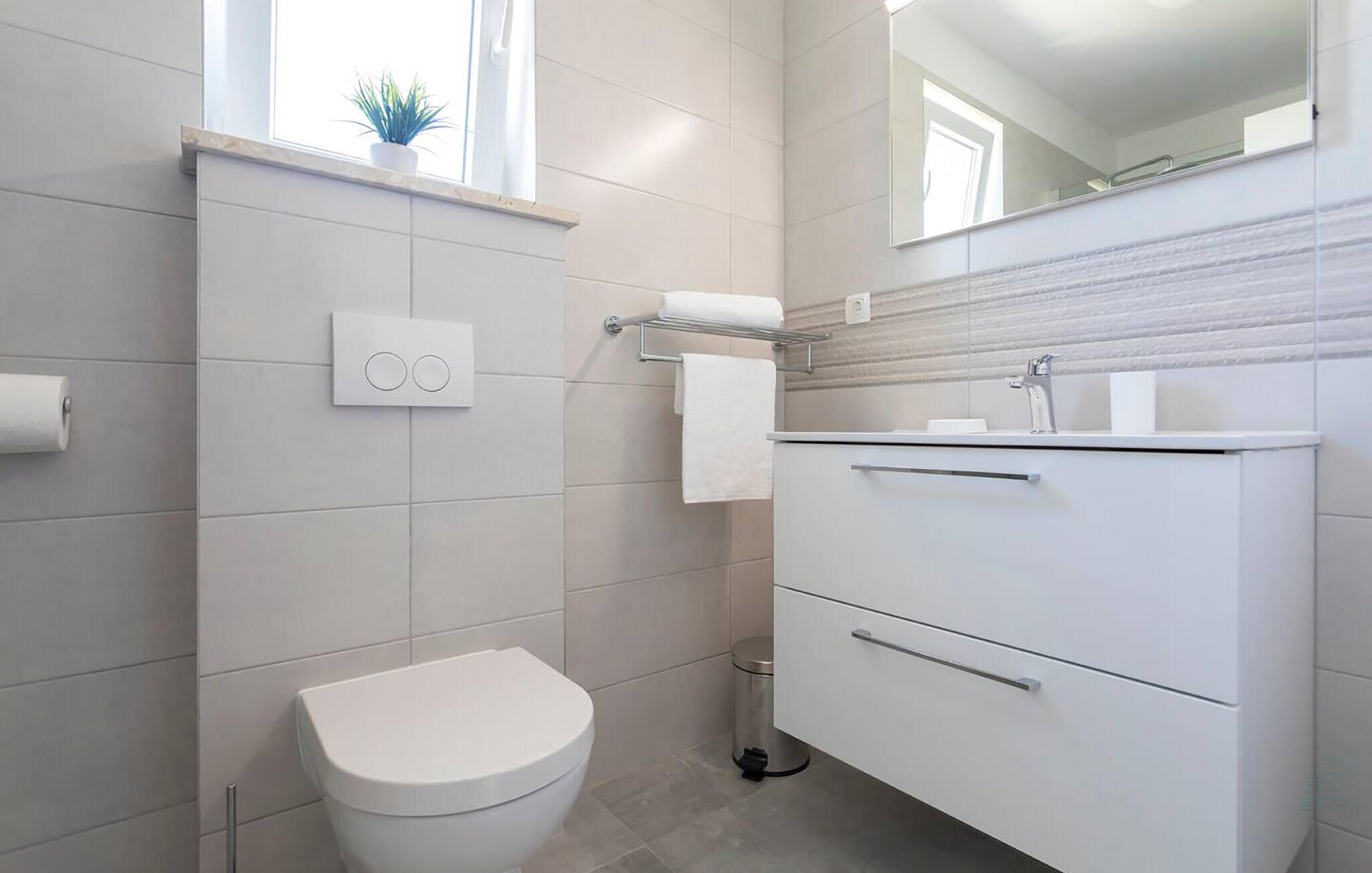 A modern bathroom with a toilet, a sink, and a mirror.