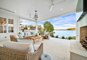 A covered outdoor seating area with wicker furniture, a fireplace, and a view of a lake. - Lakeside Luxury w/Private Heated Pool, Sleeps 15 (Hot Springs)