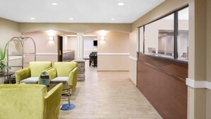 Un hall de hotel con mostrador de recepción, zona de estar con sillas y vistas amplias por ventanas grandes.