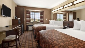 Une chambre d’hôtel avec deux lits, un bureau, une chaise, une télévision et une fenêtre avec des rideaux.